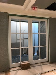 White double doors with glass panes, leading to a room under construction, with an 