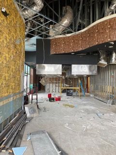 Construction site interior. Unfinished walls, exposed pipes, and debris on the floor.