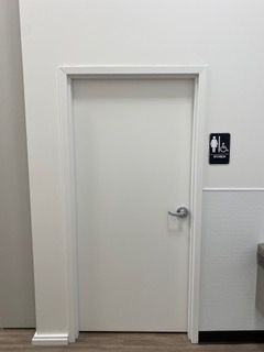 White restroom door with silver handle and accessible sign.