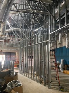 Interior construction site with metal framing for walls, ceiling, and ductwork.