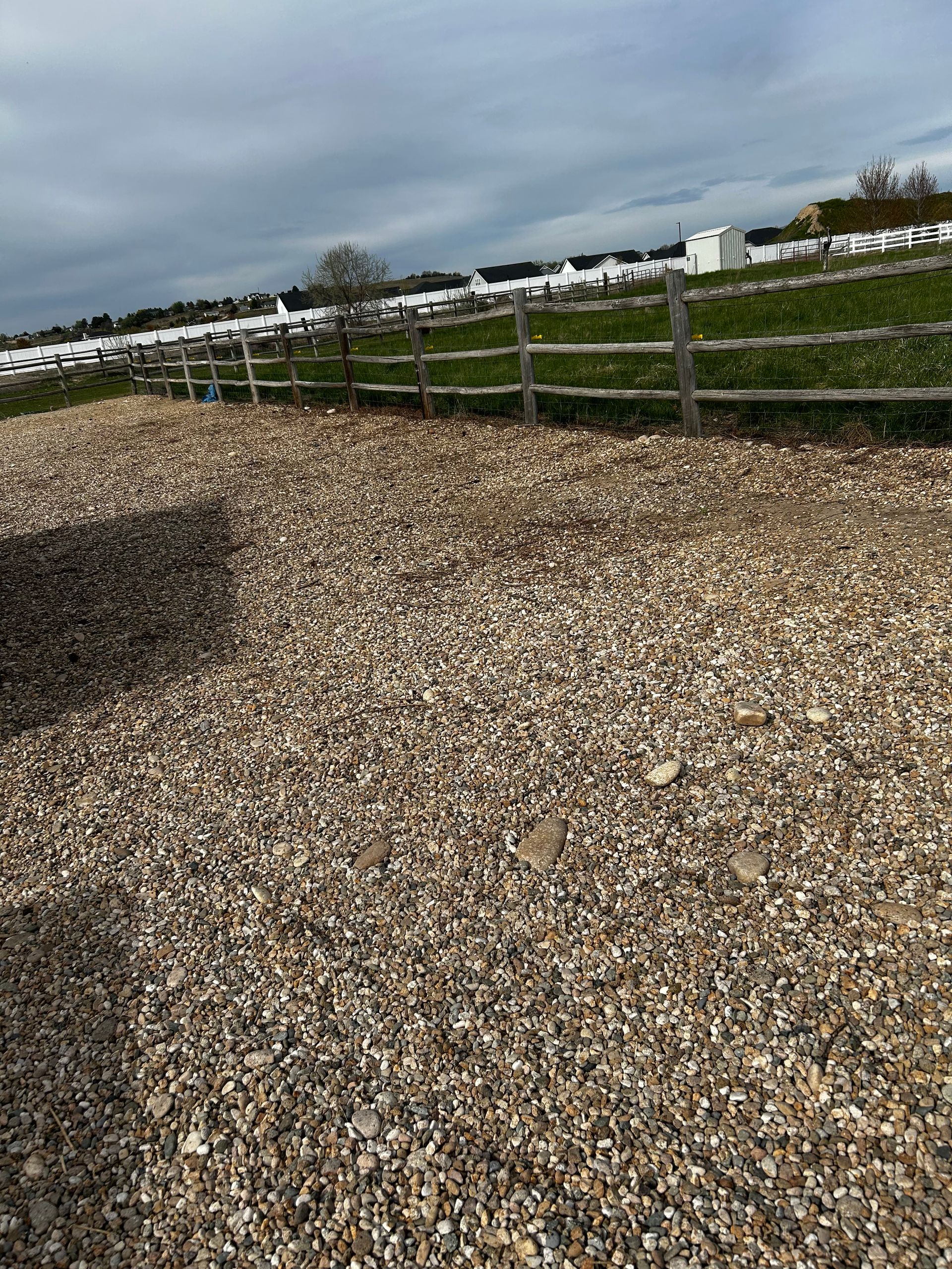 A gravel road with a wooden fence in the background.