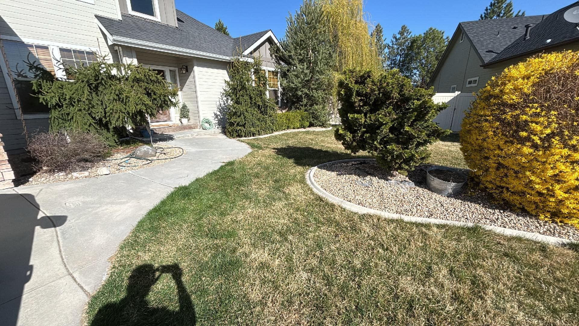A person is taking a picture of their shadow in front of a house.