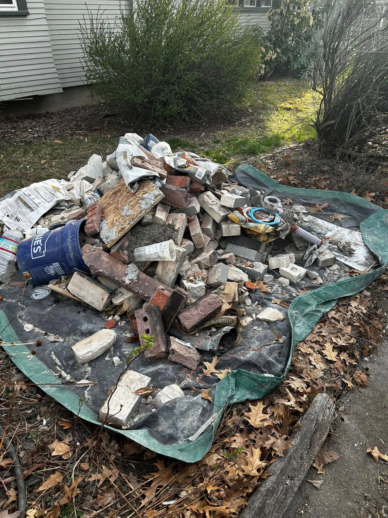 A pile of bricks is sitting on top of a green tarp.