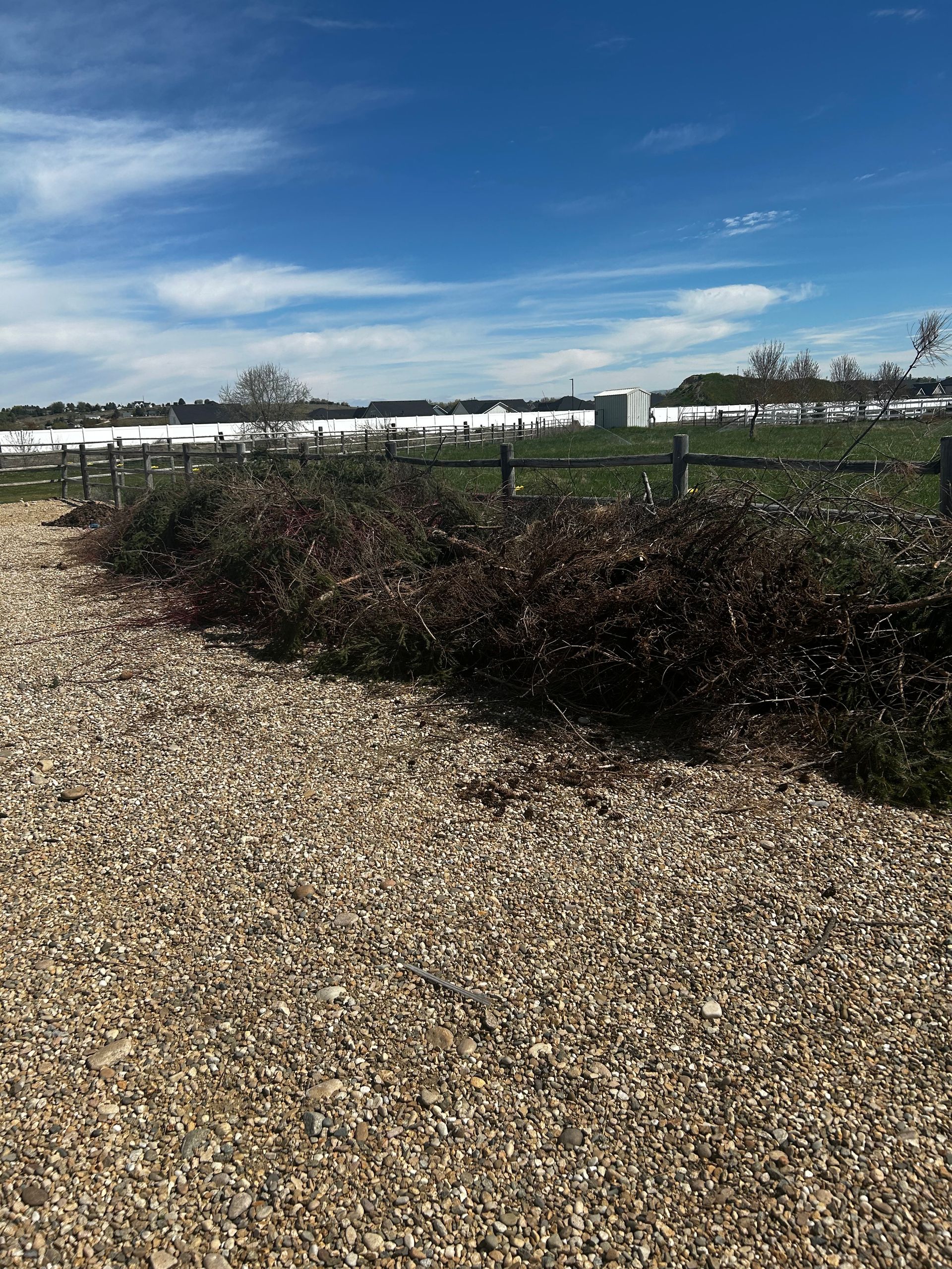 A gravel road with a fence in the background