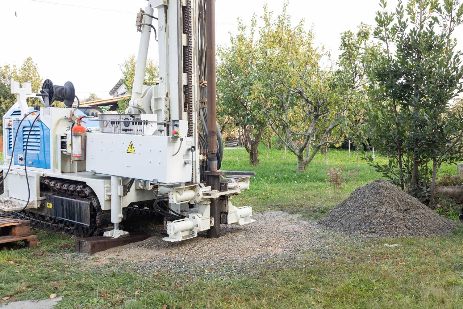 A water well drilling rig operating on a grassy residential property.