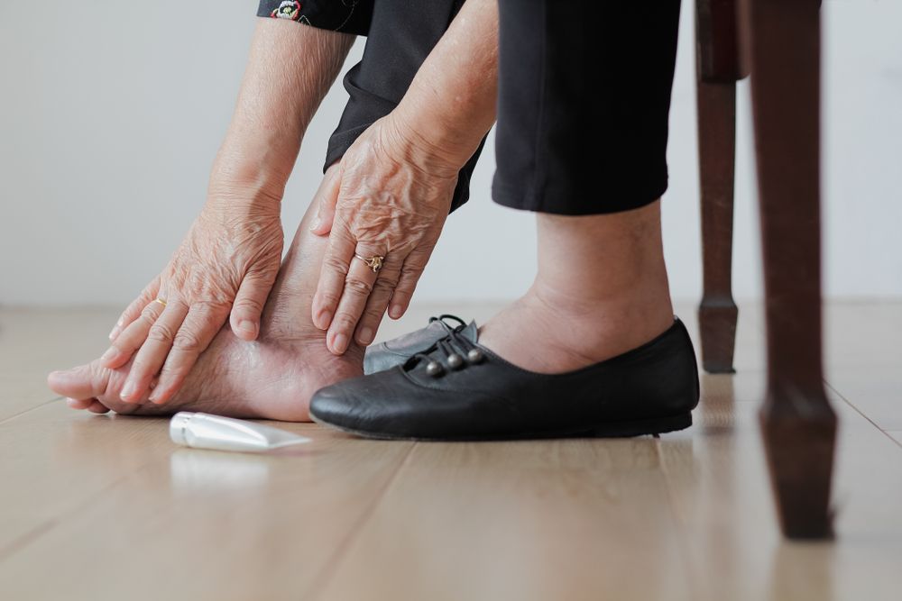 Elderly Woman Putting Cream on Swollen Feet Before Put on Shoes — Providing Diabetes Foot Assessments in Forster, NSW