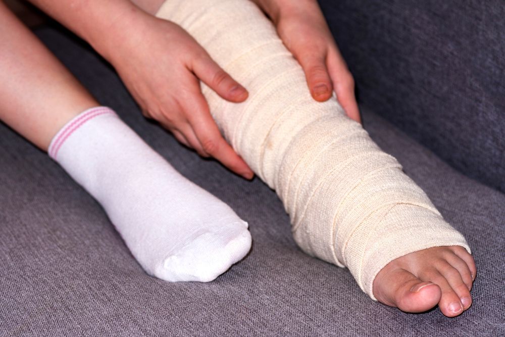 Woman Applying Bandage to Foot on the Floor — Providing Diabetes Foot Assessments in Forster, NSW