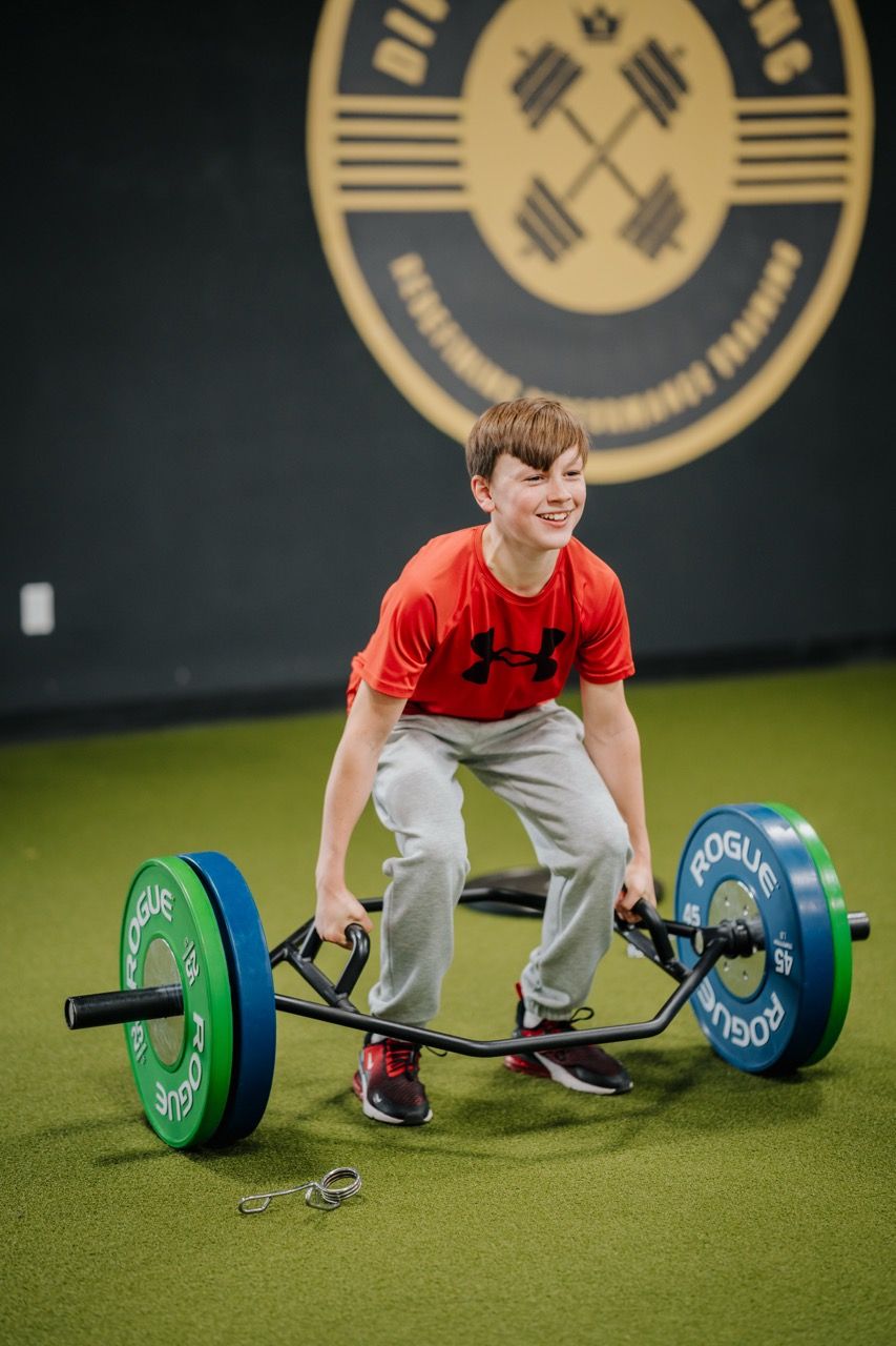 Young athlete in a red shirt preparing to lift a barbell in Division X Training in Branford, CT