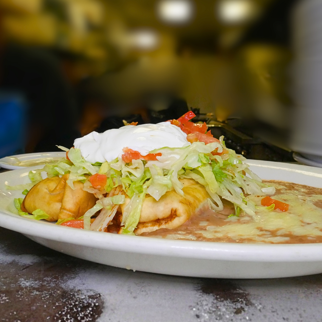 Chimichanga - soft or crispy fried tortilla filled with shredded beef, chicken, or shrimp, topped with cheese sauce, lettuce, guacamole, tomato, sour cream.