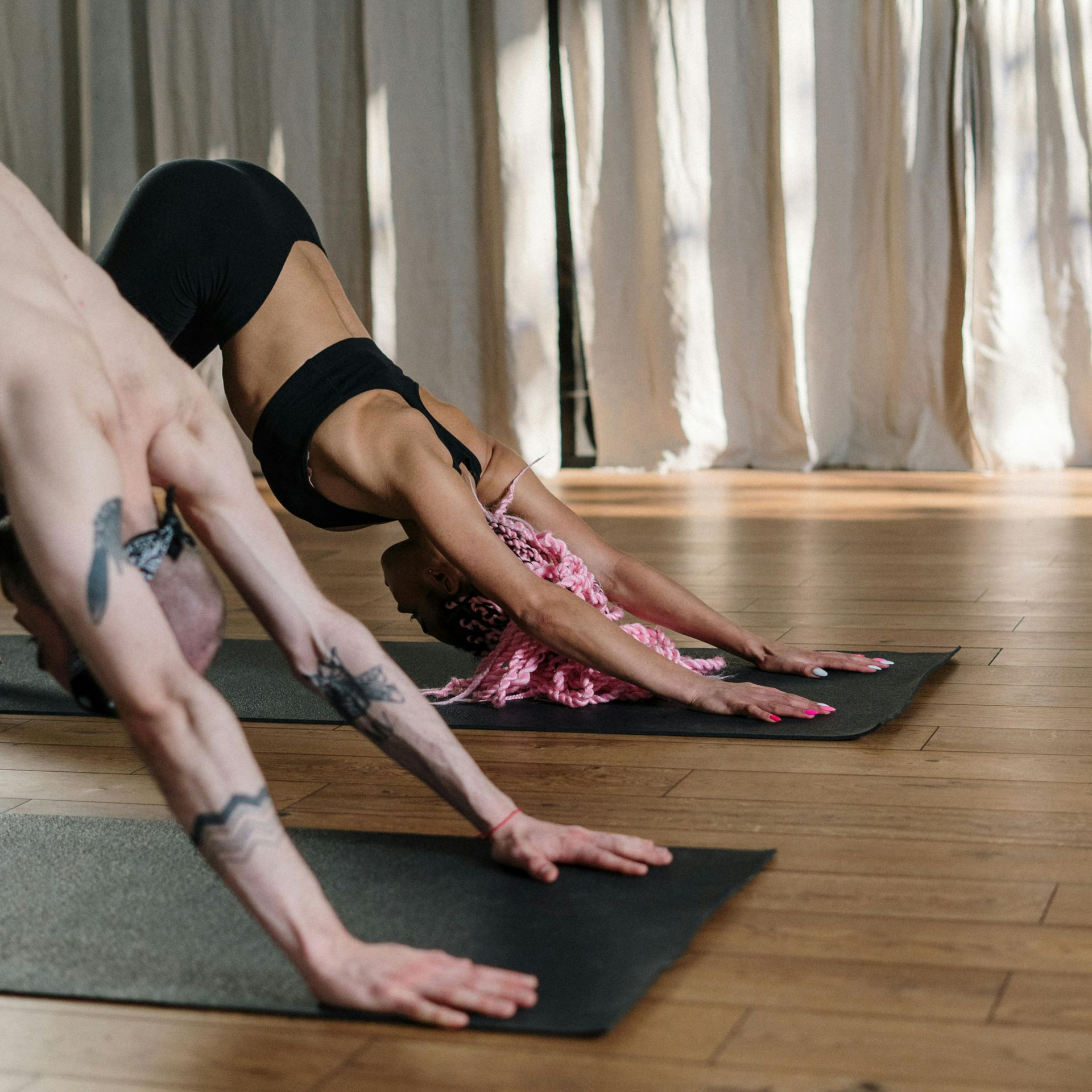 2 People doing downward dog in a yoga class