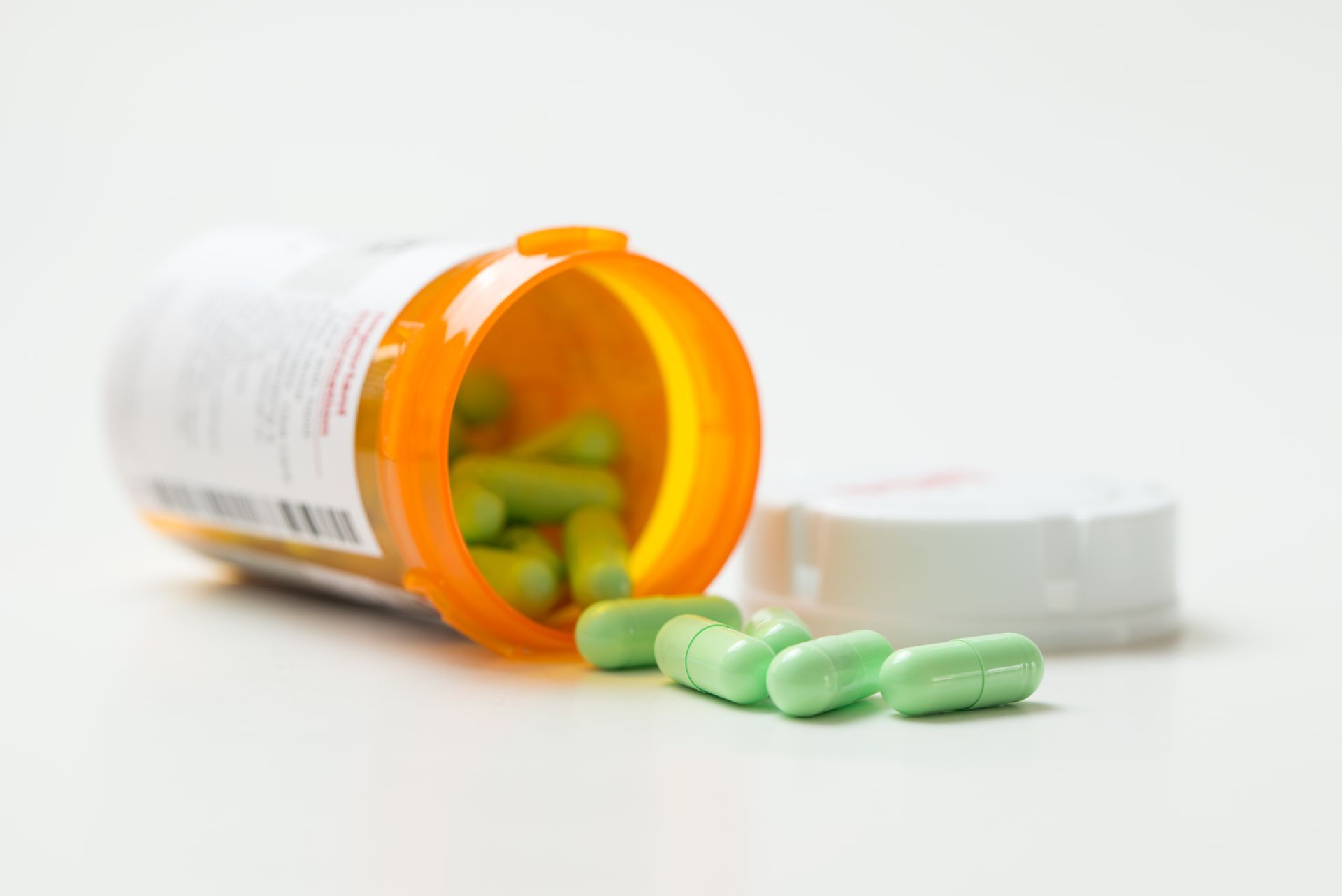 A photo of a pharmaceutical pill bottle and plastic cap.