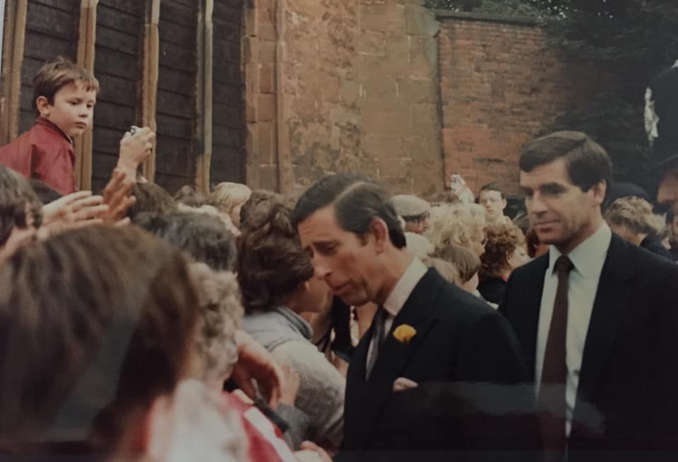 A man in a suit and tie is walking through a crowd of people.