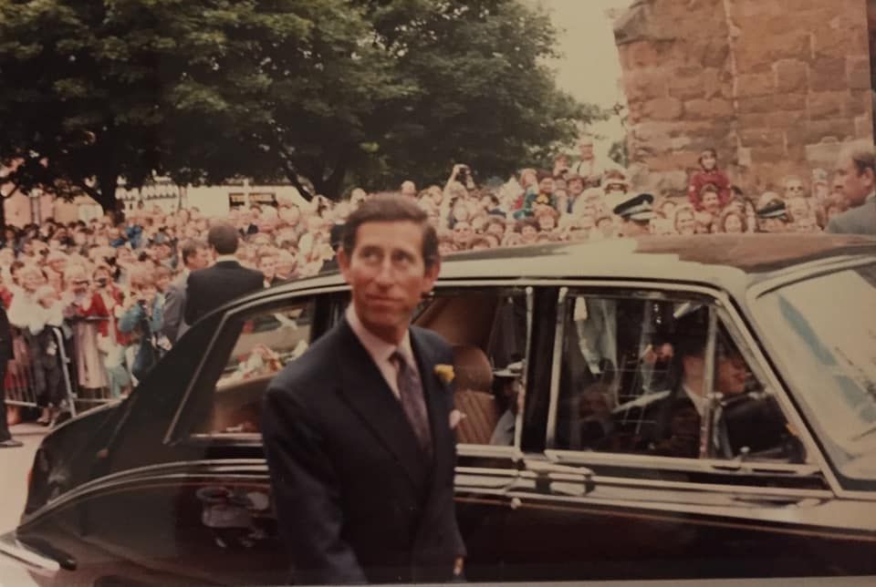 A man in a suit and tie is standing next to a car