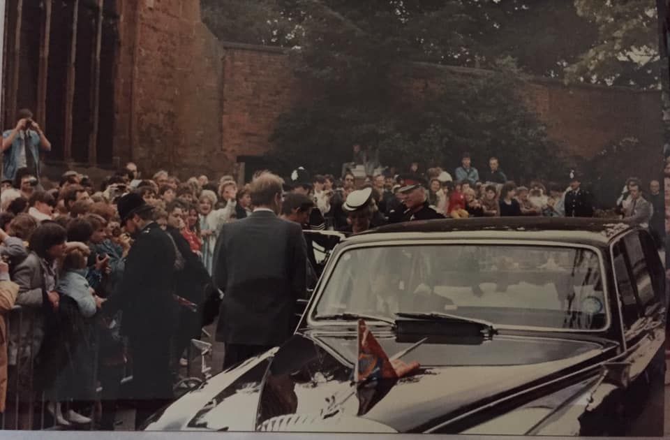 A group of people are gathered around a black car