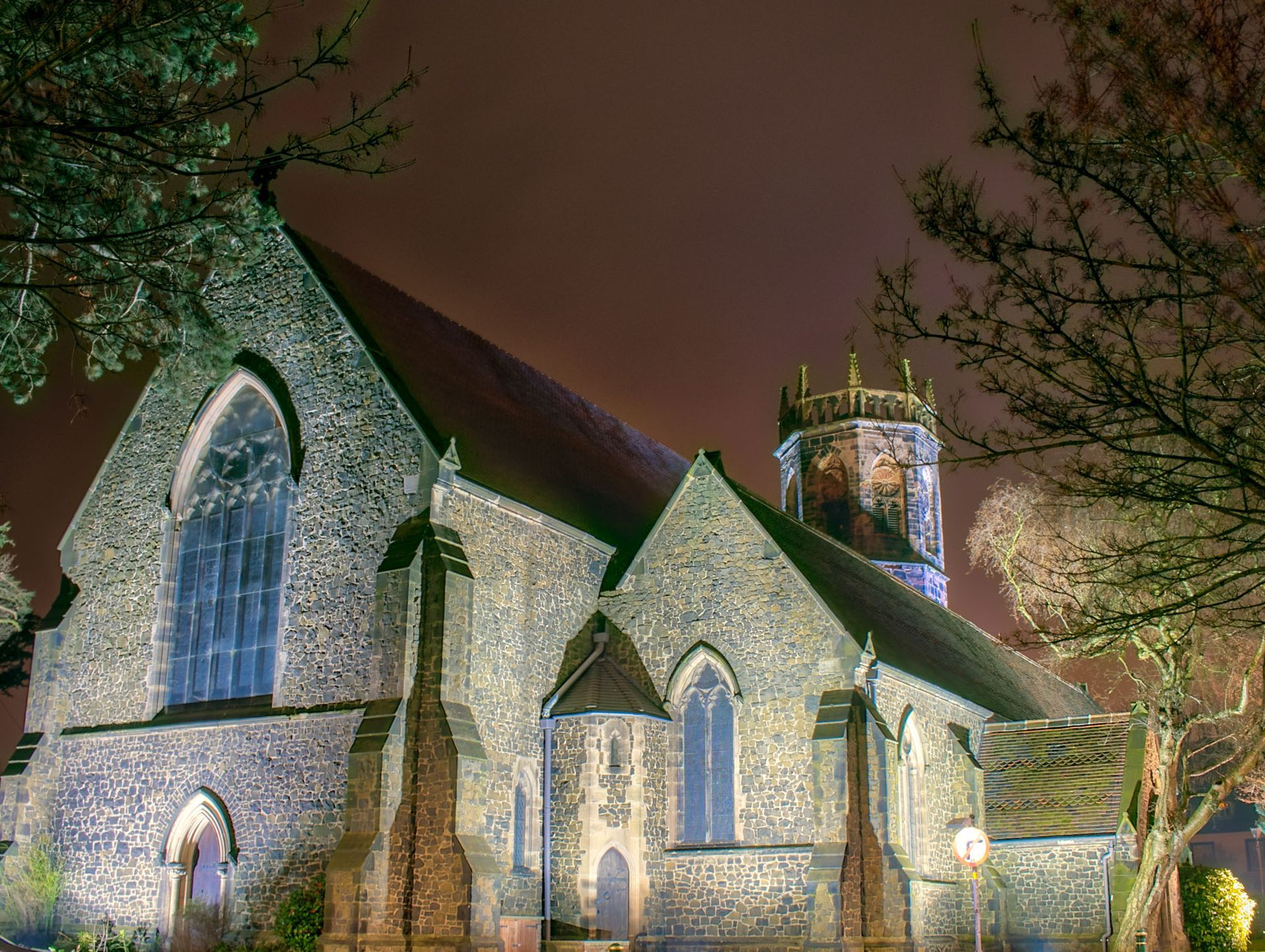 A church is lit up at night with trees in the foreground