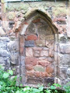 A stone wall with a doorway in the middle of it surrounded by plants. st mary's atherstone warwickshire