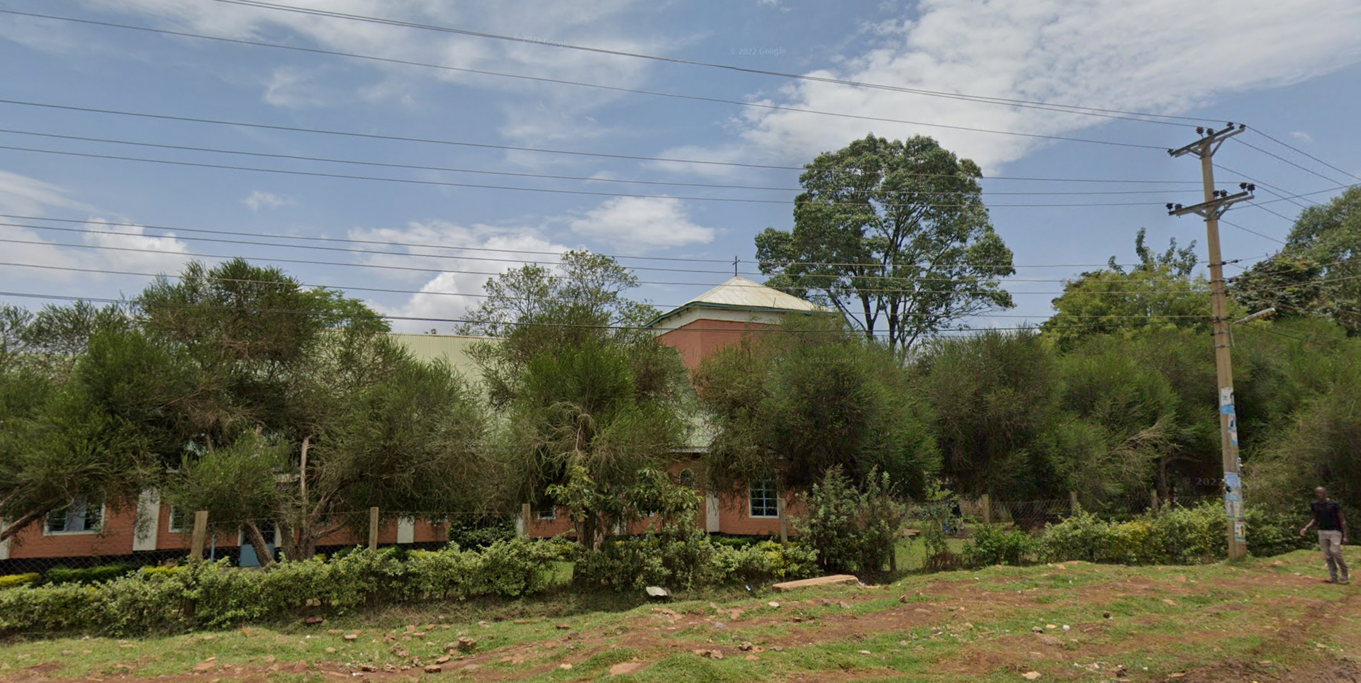 A large brick building is surrounded by trees and power lines.