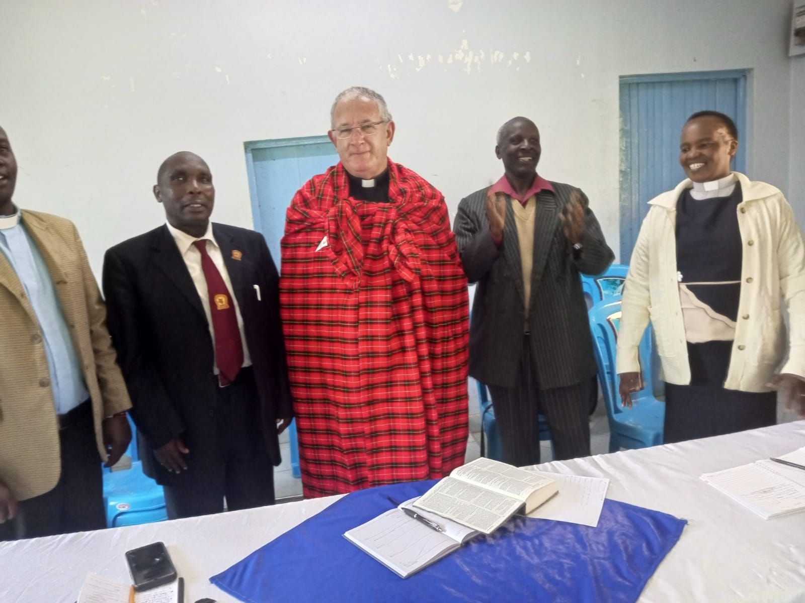 A group of people standing around a table with a bible on it