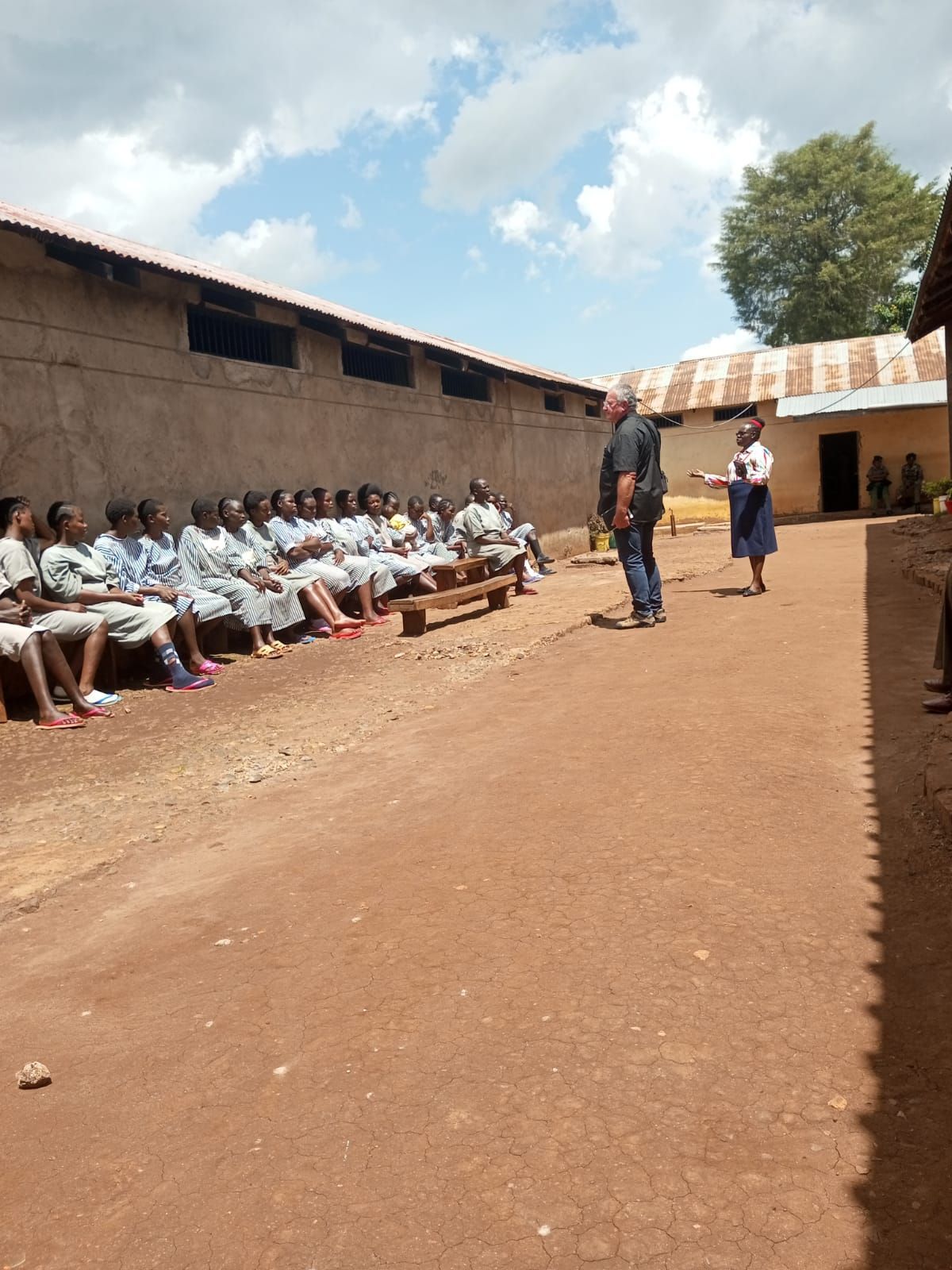 A group of people are sitting on benches outside of a building.