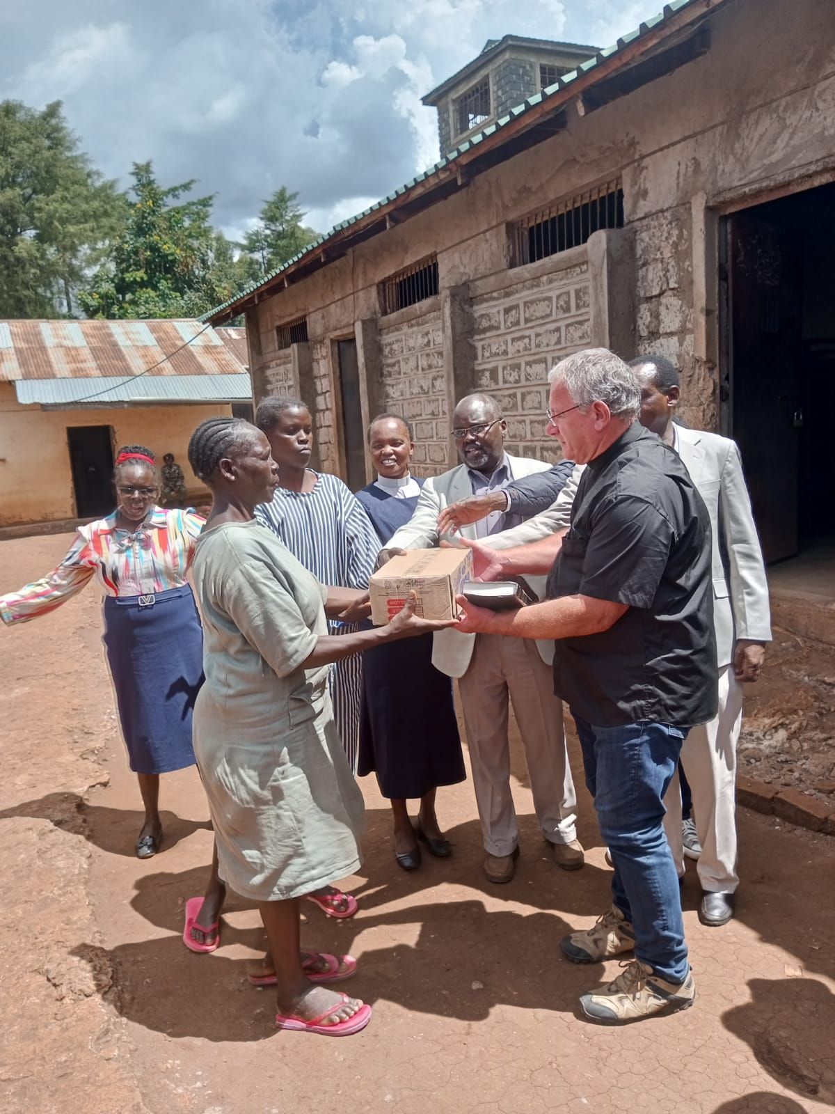 A man is giving a box to a woman in front of a group of people.