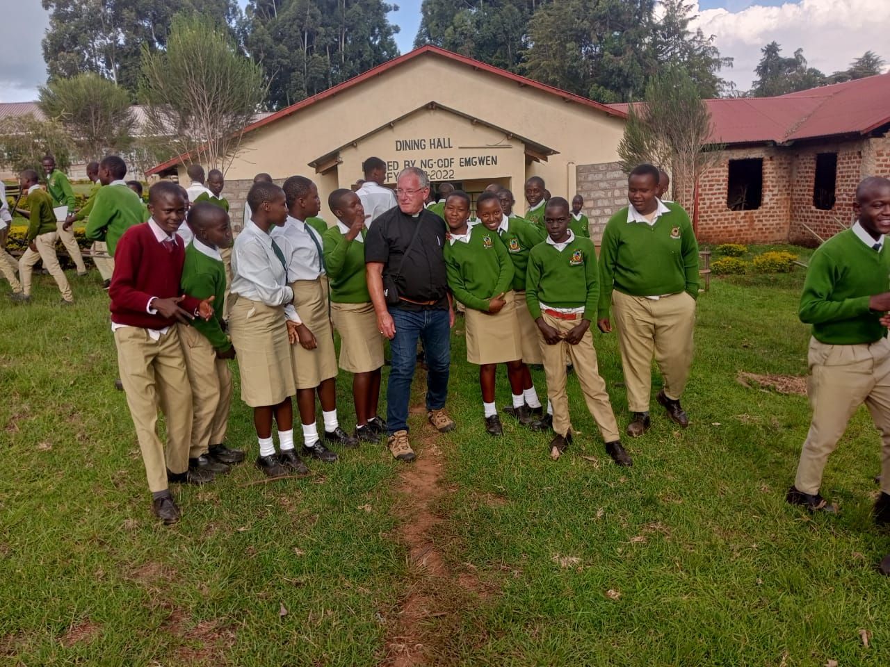 A group of children in school uniforms are standing in front of a building.