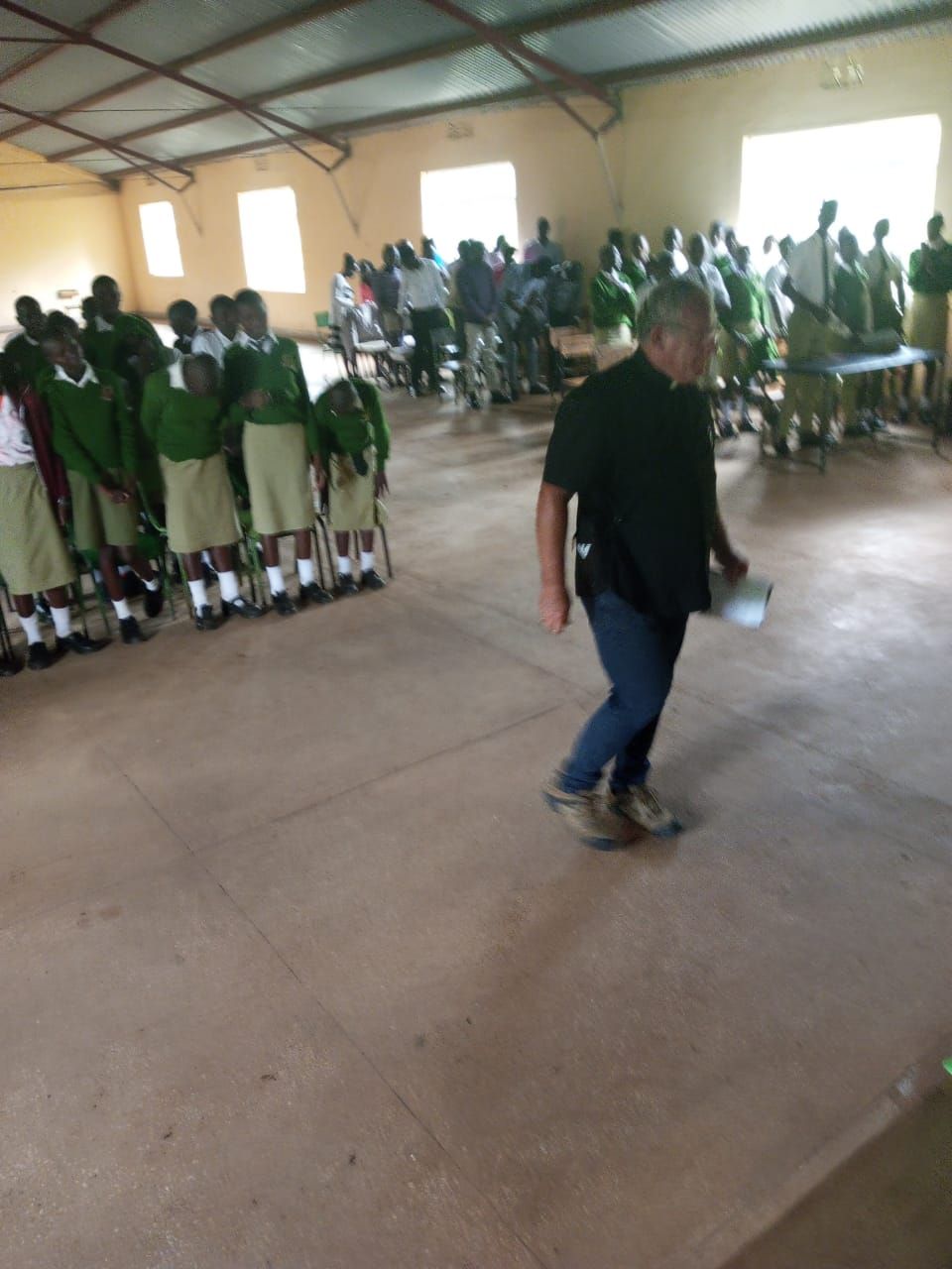 A man in a black shirt is walking in front of a large group of people