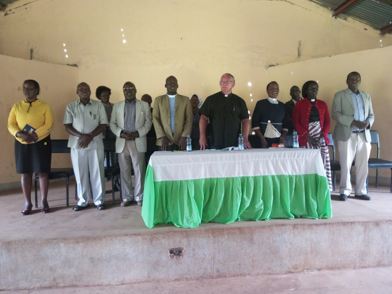 A group of people standing around a table with a green table cloth