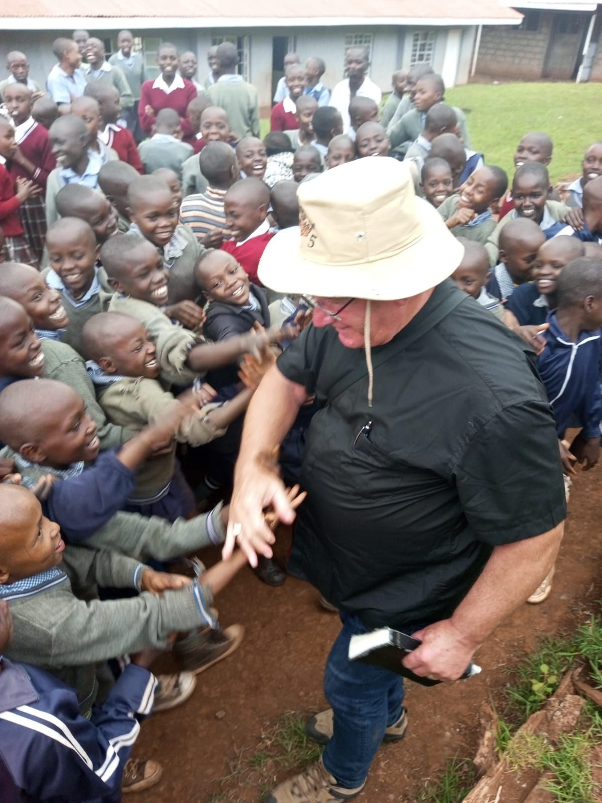 A man in a hat stands in front of a crowd of children
