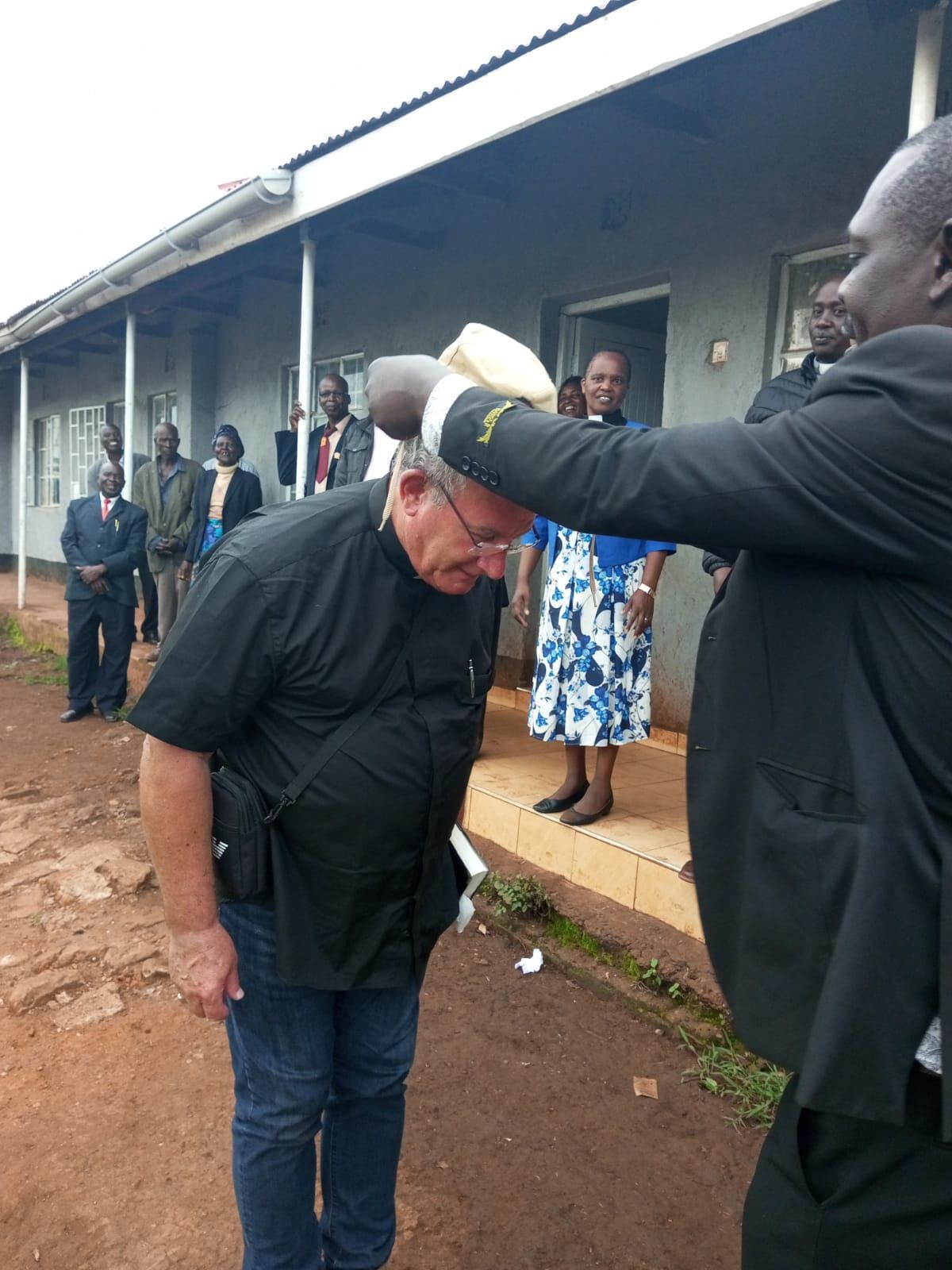 A man in a suit is giving a man a hat