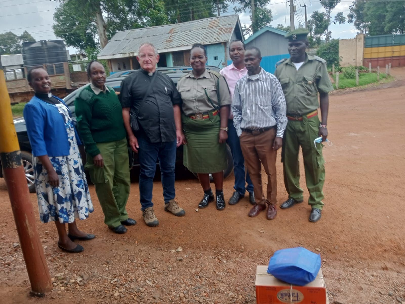 A group of people standing next to each other on a dirt road.