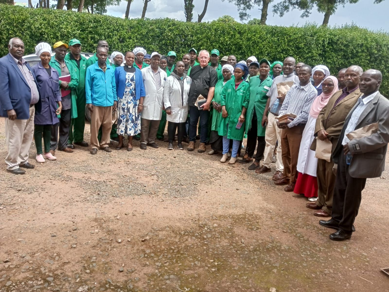 A group of people are posing for a picture in a dirt field.