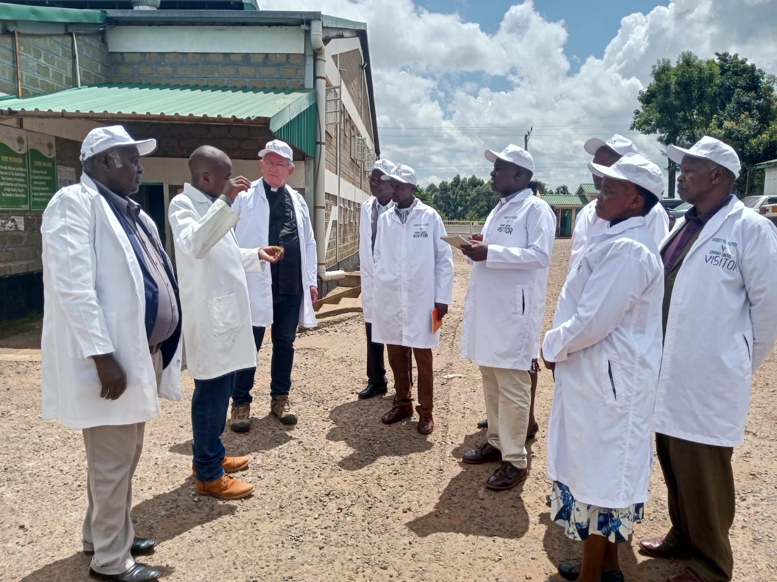 A group of people in white coats and hats are standing in front of a building.
