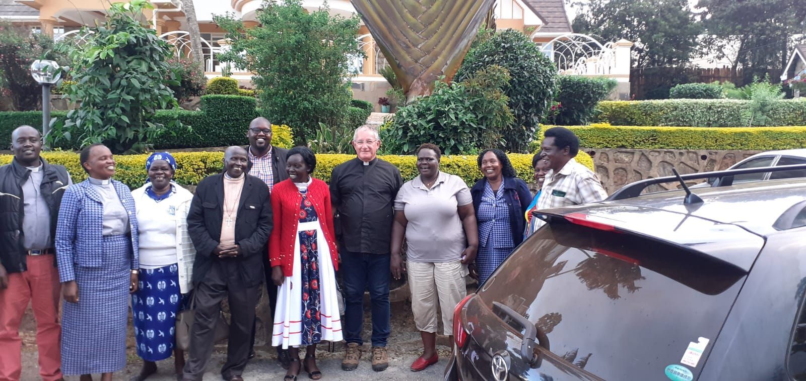 A group of people are posing for a picture in front of a car.