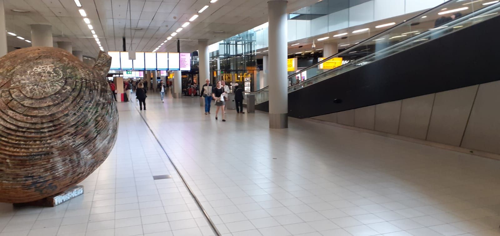 A large sculpture is sitting in the middle of an airport terminal.