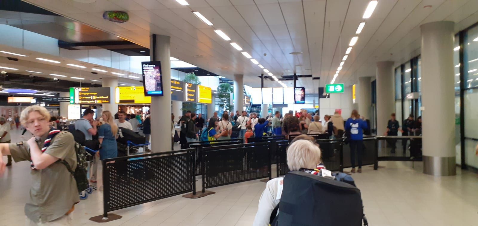 A woman in a wheelchair is waiting in a crowded airport.