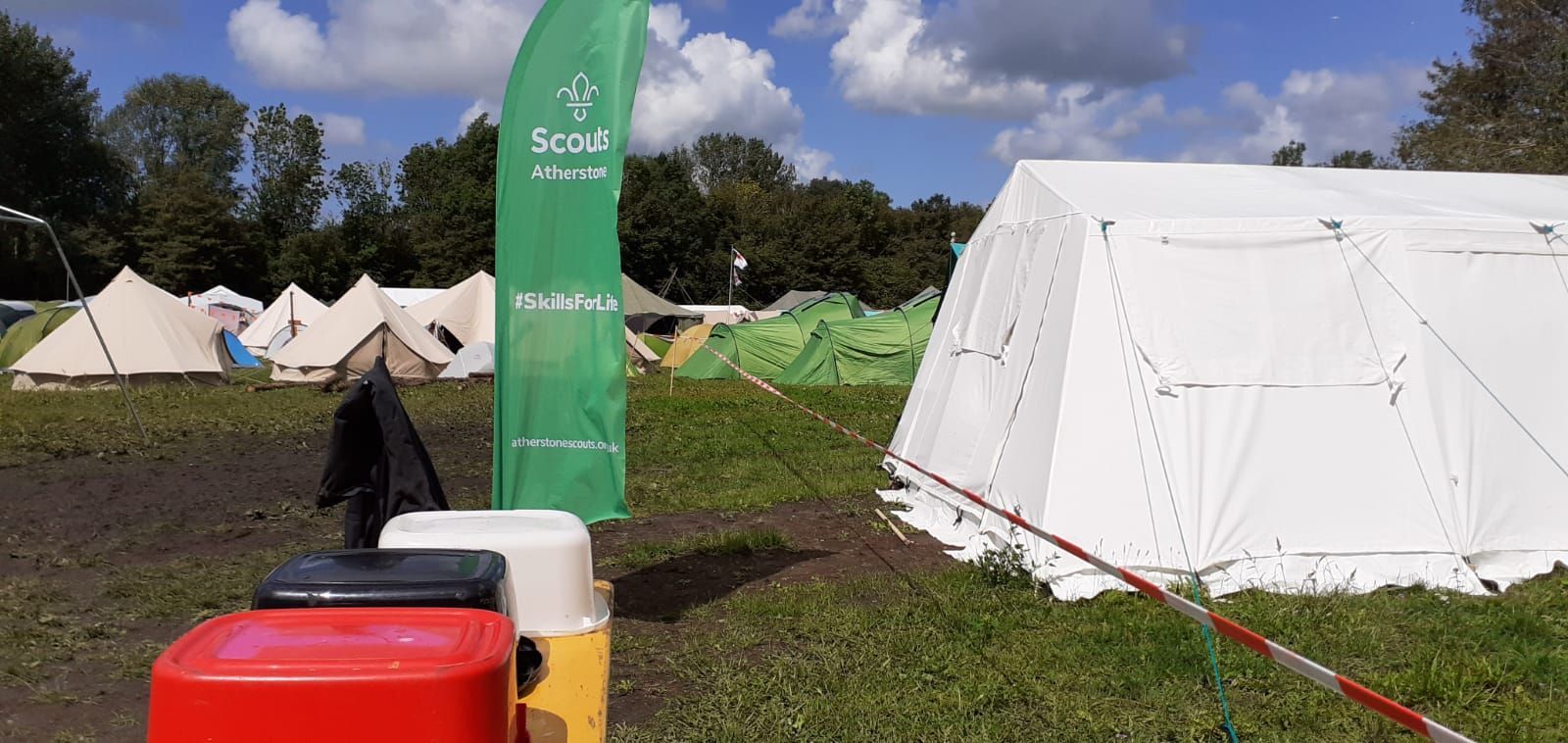 A group of tents are sitting in a field next to a green flag.