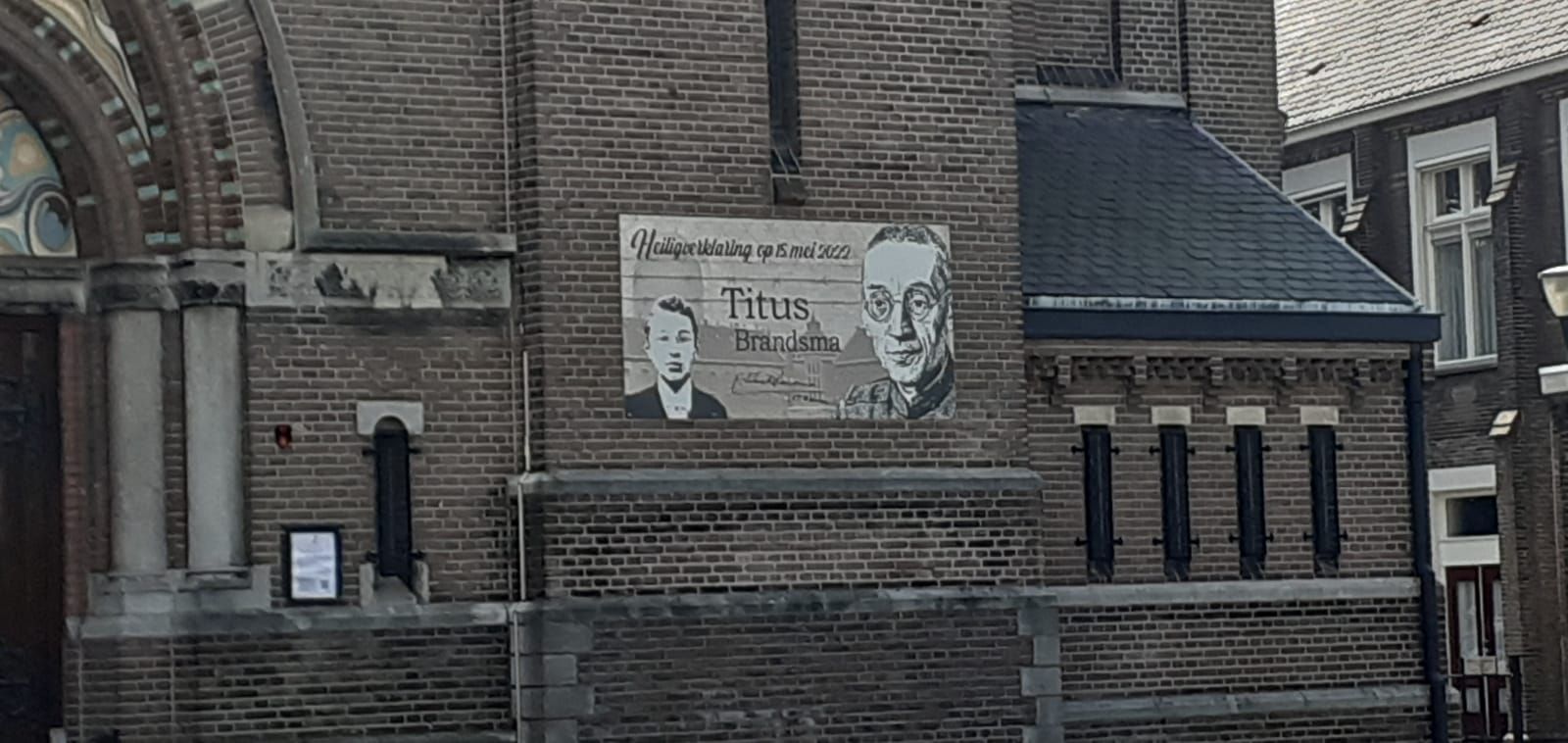 A black and white photo of a brick building with a sign on the side.
