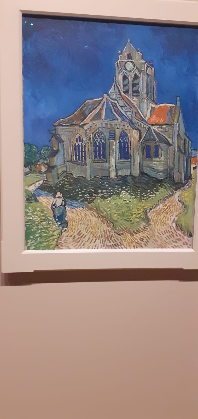 A painting of a church by vincent van gogh is hanging on a wall.