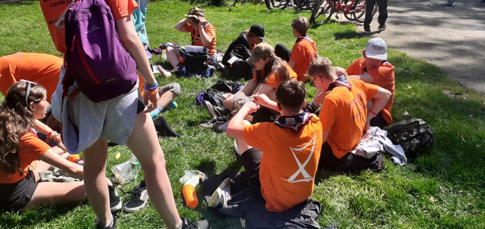 A group of people in orange shirts are sitting in the grass.
