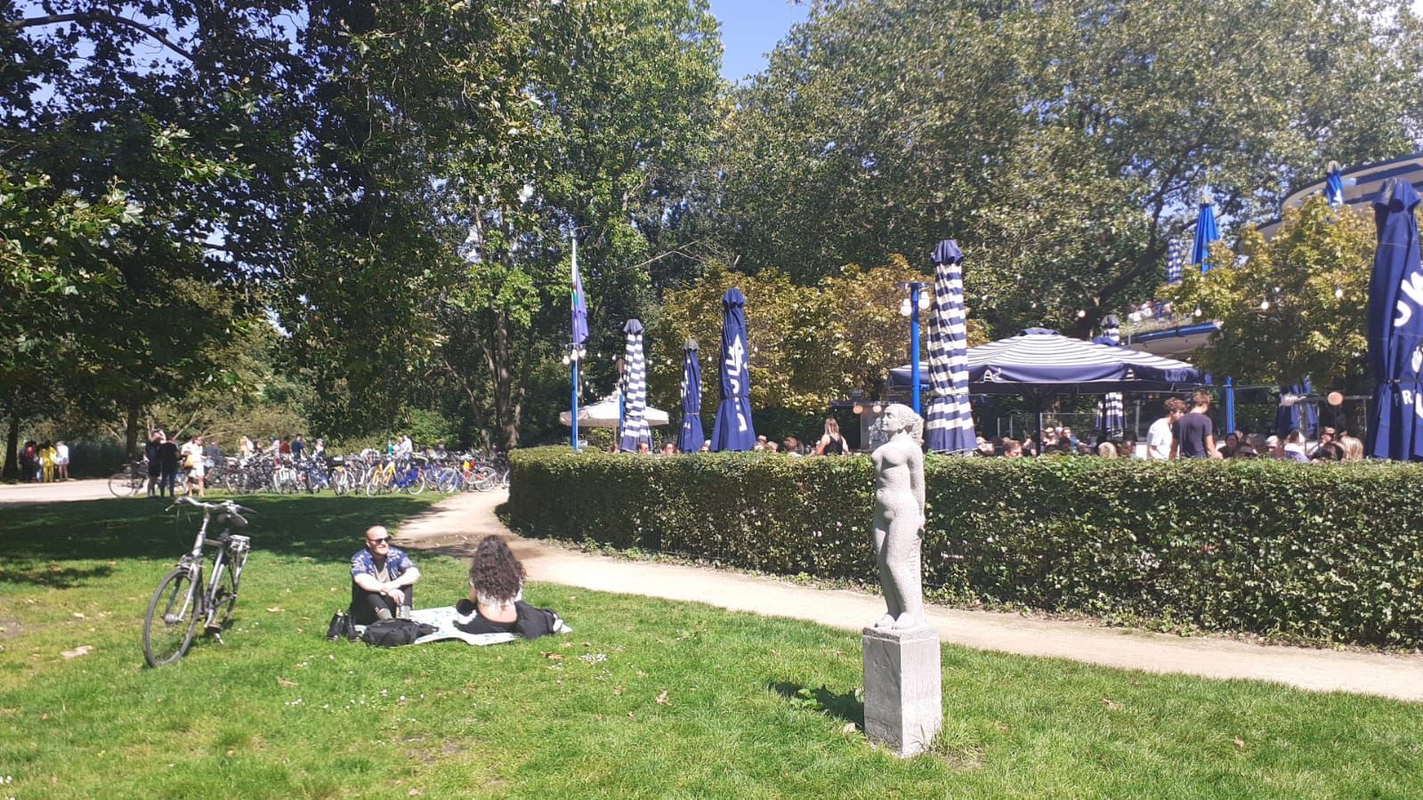 A group of people are sitting on the grass in a park.