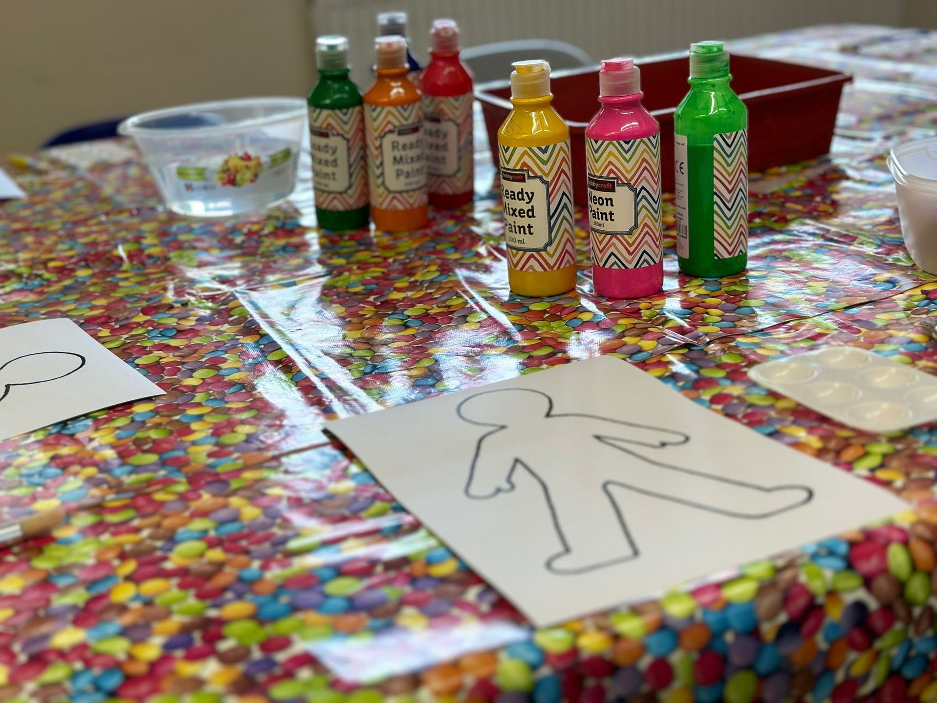 A table with bottles of paint and a drawing of a person on it.