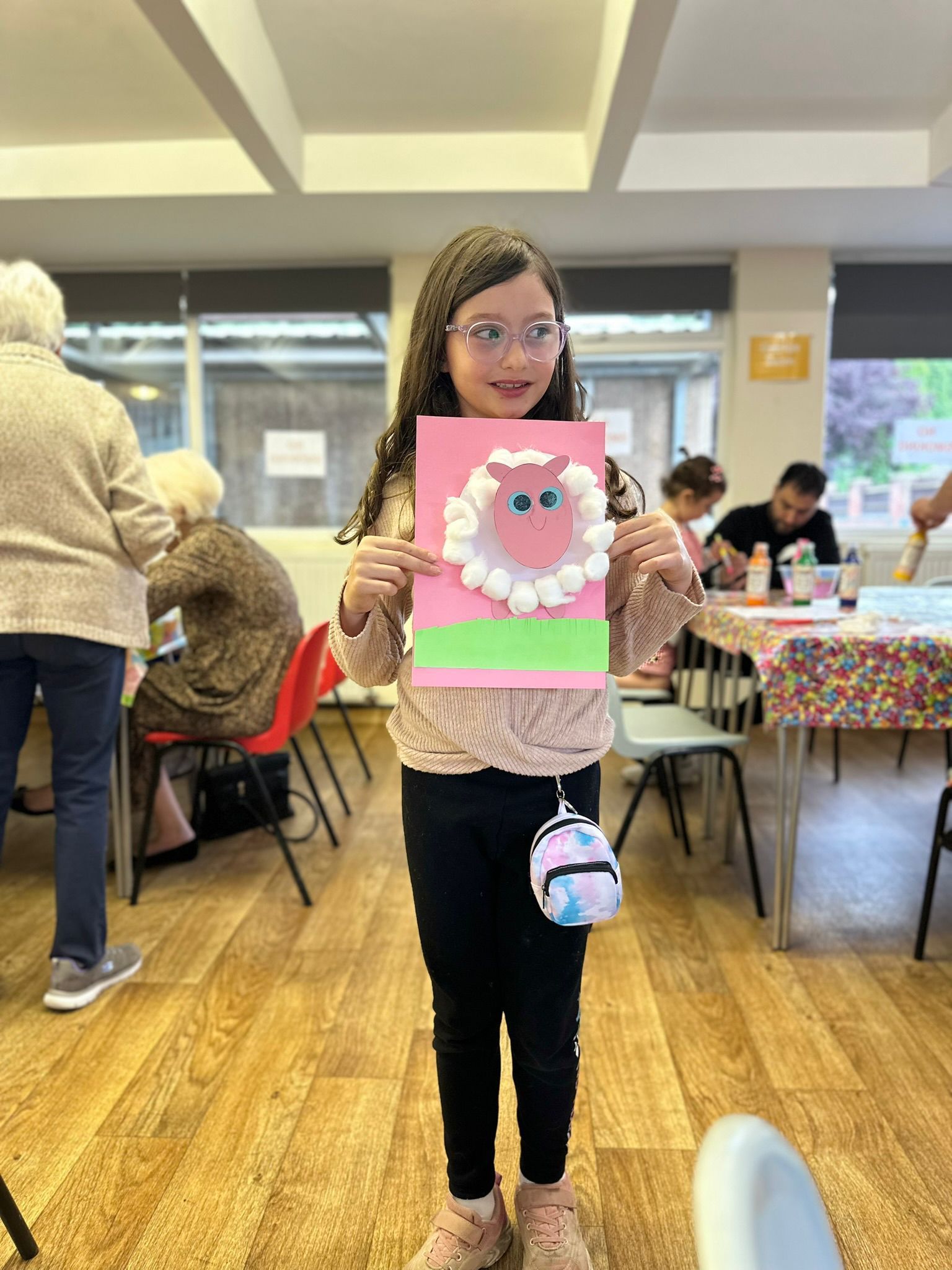 A little girl is holding a card with a picture of a sheep on it.