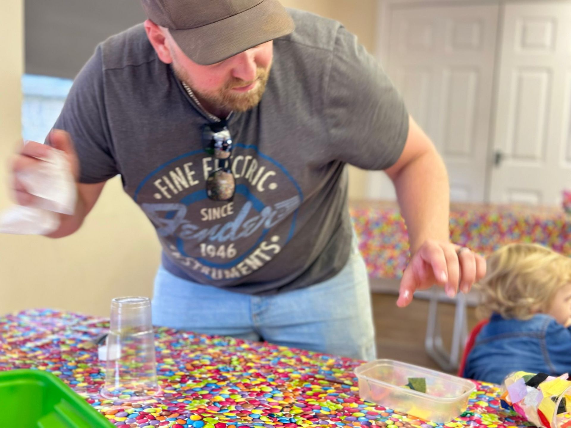 A man in a fender shirt is standing at a table with confetti.