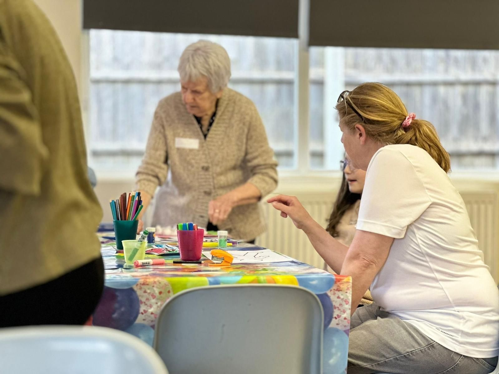 A group of women are sitting at a table making crafts.