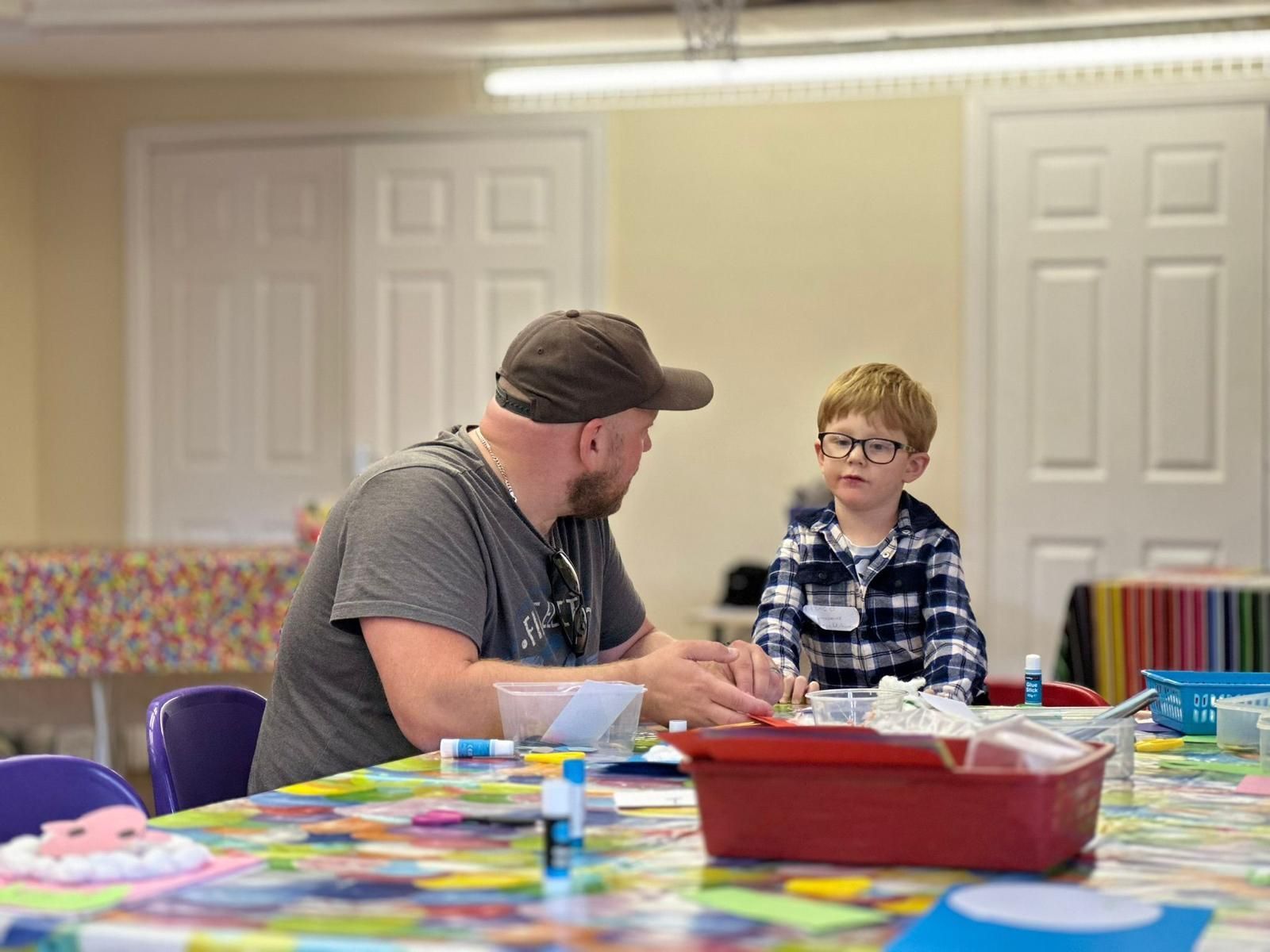 A man and a boy are sitting at a table talking to each other.