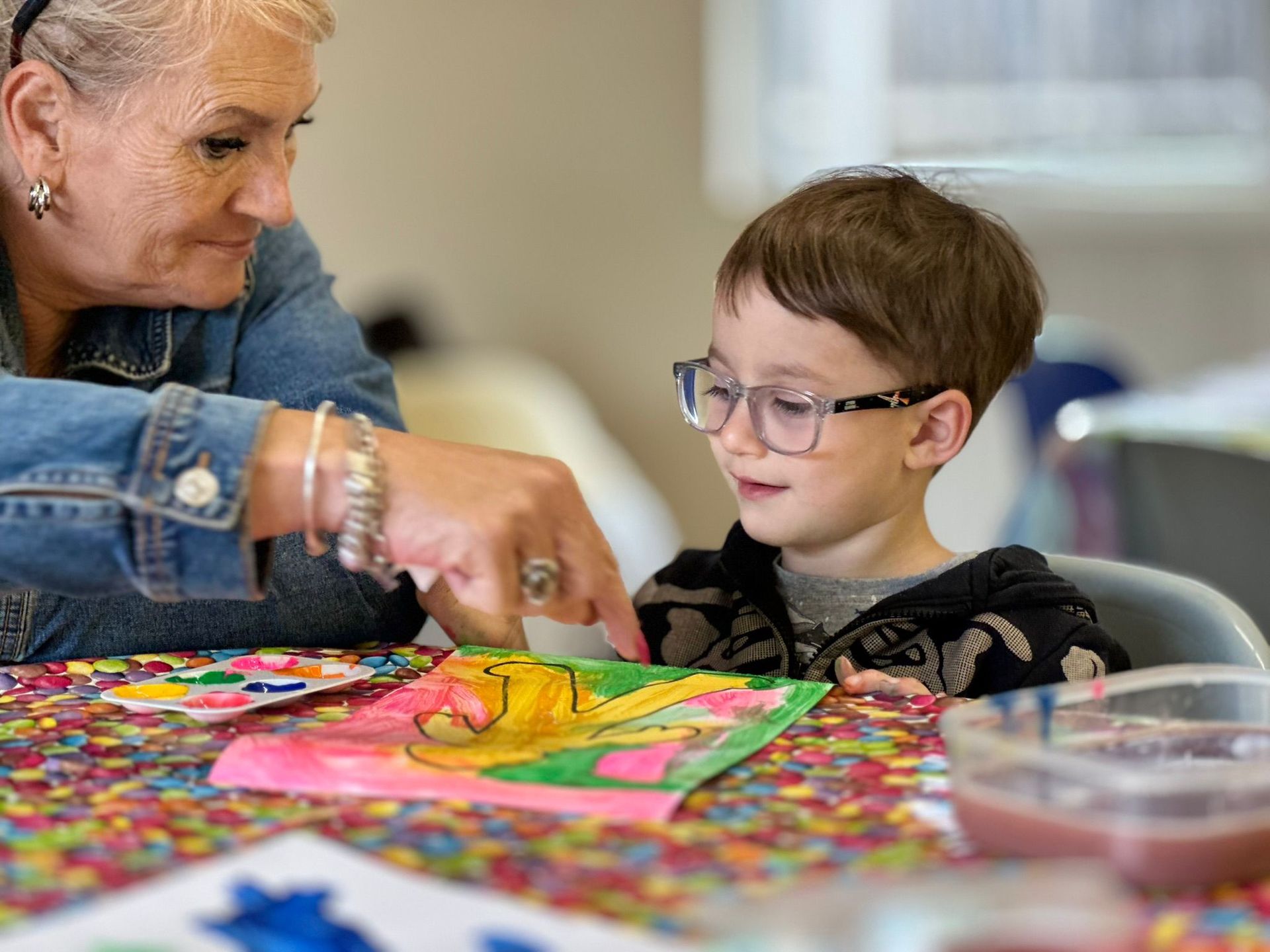 A woman is teaching a young boy how to paint a picture.