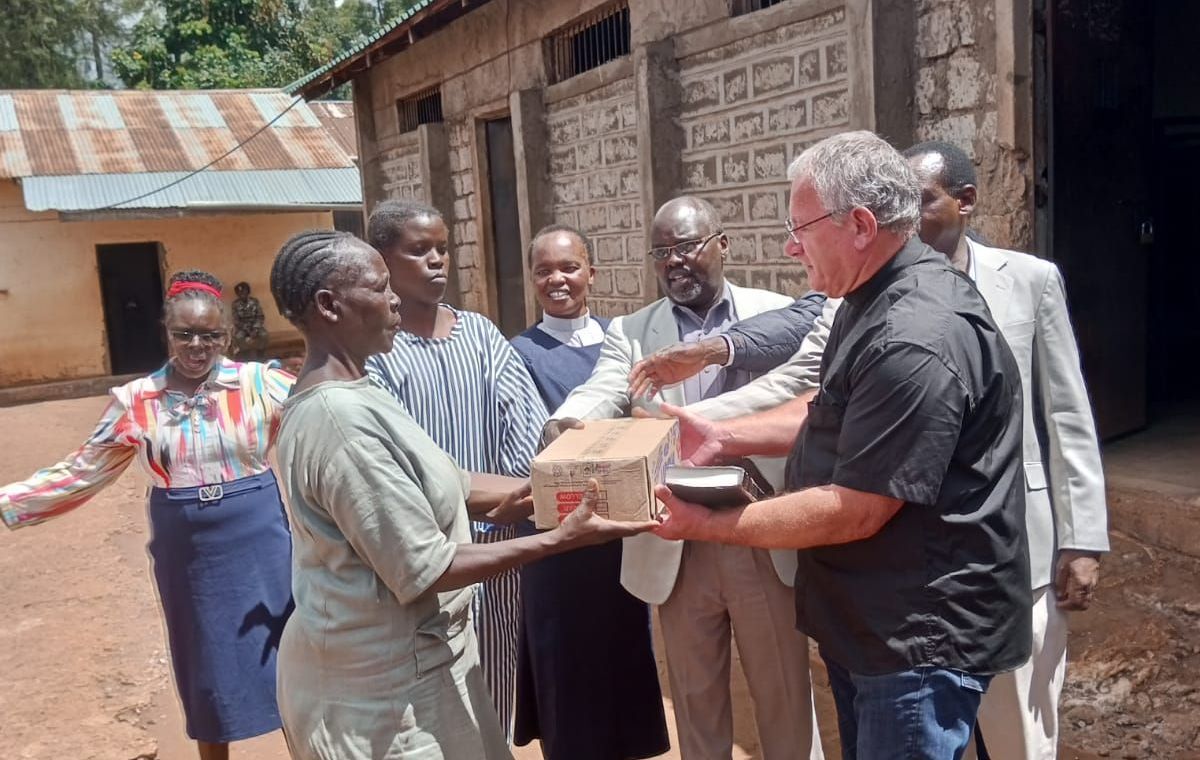 A man is giving a box to a woman in front of a group of people.