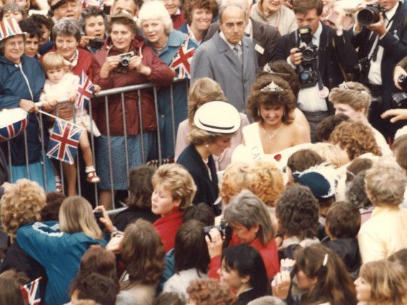 A crowd of people are gathered around a fence with british flags