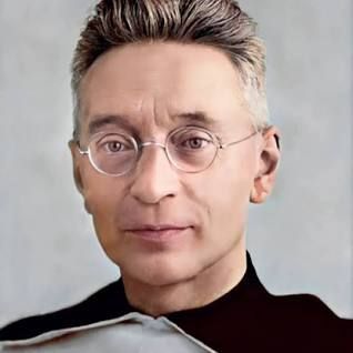 A man wearing glasses and a black shirt is looking at the camera.