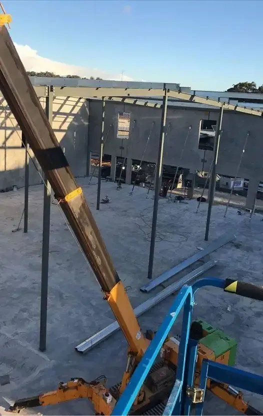 A Crane Is Sitting on The Ground in Front of A Building Under Construction — Mayric Engineering in  Old Bar, NSW